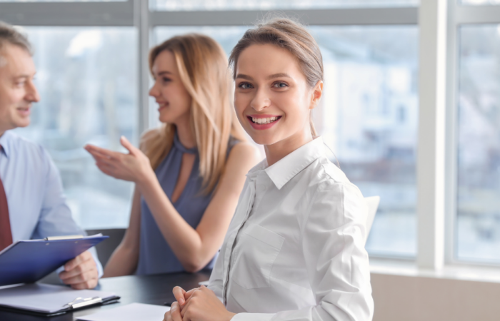 Naeratav kontoritöötaja koos kolleegidega – professionaalne personalijuhtimine ja meeskonna areng